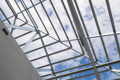 Structure of steel roof frame with blue sky and clouds at constr